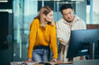 © Liubomir - Close-up photo, a team of 2 office workers, an Asian man and a woman looking at a computer monitor