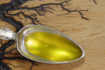 Spoon with fish oil in metal spoon in metal spoon on wooden background. Omega 3 vitamins in spoon close-up