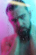 © blackday - Portrait of handsome young man captured through wet glass in colorful light