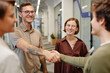 © Seventyfour - Portrait of modern business team welcoming new employee focus on smiling tattooed man shaking hands with intern