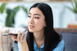 © kucherav - Portrait asian young woman is sending audio voice message by her smartphone or searching information in network