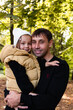 © Sarbinaz Mustafina - Dad and daughter are hugging and looking at the camera. Summer park. Green trees. The concept of a young family.
