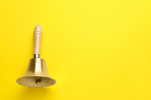 Golden School Bell With Wooden Handle On Yellow Background, Top View. Space For Text