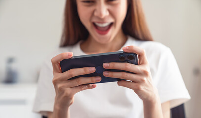 Wall Mural - Young Asian woman hand playing games on smartphone, lifestyle leisure in living room at home.