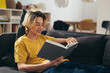 © cherryandbees - teenager reading book while sitting on couch at home