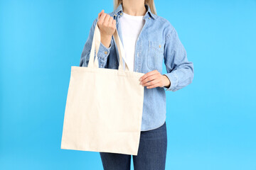 Wall Mural - Woman holds white eco bag on blue background