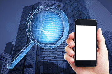 Close up of hand holding empty white mock up smartphone with abstract polygonal magnifying glass on blurry city background. Technology, information, search and business network concept. 