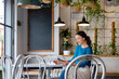 © Westend61 - Smiling barista calculating at table in illuminated cafe