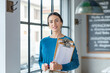 © Westend61 - Smiling cafe owner with menu on clipboards in coffee shop
