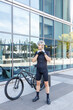 © Westend61 - Young man wearing cycling helmet by bicycle in front of office building