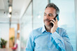 © Westend61 - Smiling businessman talking on mobile phone in corridor at workplace