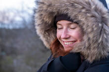 Young Woman In Fur Hooded Coat Smiling With Eyes Closed