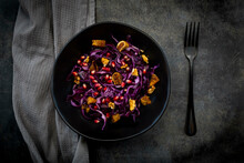 Studio shot of bowl of vegan salad with red cabbage, pomegranate seeds, dried figs and walnuts