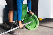 Athlete Putting Weight Plates In Barbell Before Exercising In Gym