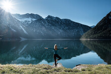 Woman Practicing Yoga At Lake Plansee, Ammergau Alps, Reutte, Tyrol, Austria