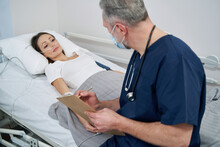Male Physician Taking Notes Of Female Patient Health Status