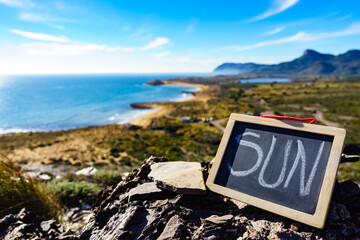 Wall Mural - Black board with word sun against sea coast