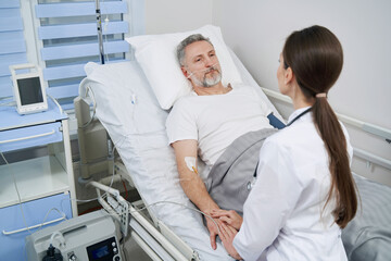 Attending doctor examining mature man with intravenous line