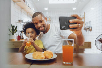 Wall Mural - Happy African American Fther and little kid boy taking selfie with smartphone