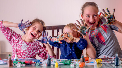 Happy children with funny facial expressions and painted hands drawing and having fun. Concept: carefree happy childhood, learning art and creativity.  Horizontal image.