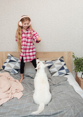 Wall Mural - Girl in headphones playing with her dog