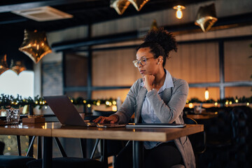 Concentrated African-American woman with a ponytail, working as a restaurant manager.