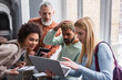 © LIGHTFIELD STUDIOS - Interracial students looking at laptop near teacher in university corridor