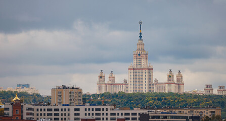 Wall Mural - travel to moscow, russia, main tourist attractions. view of Stalin skyscraper against backdrop of green trees in park. Lomonosov Moscow State University