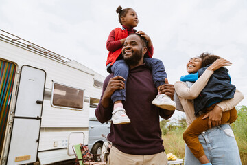 Wall Mural - Black parents laughing while playing with their children by trailer