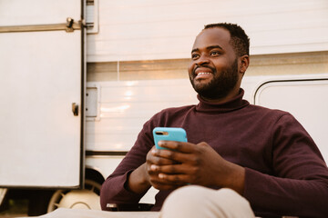 Wall Mural - Black man using mobile phone during journey on trailer