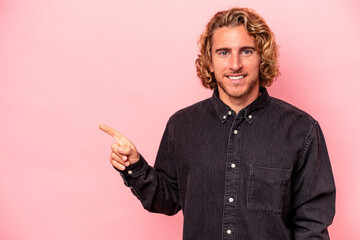 Wall Mural - Young caucasian man isolated on pink background smiling cheerfully pointing with forefinger away.