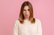 Portrait of blond woman sticking out tongue and looking at camera, teasing with naughty expression, disobedient behavior, wearing white sweater. Indoor studio shot isolated on pink background.