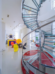 Modern interiro of luxury private house. Glass metal spiral staircase.