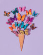 Colorful butterflies flying from ice cone on pastel purple background. 80s, 90s retro aesthetic romantic spring or summer concept. Minimal fashion idea.