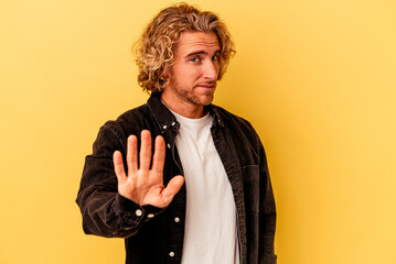 Wall Mural - Young caucasian man isolated on yellow background rejecting someone showing a gesture of disgust.