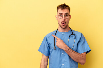 Wall Mural - Young nurse caucasian man isolated on yellow background pointing to the side