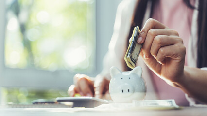 Closeup of businesswoman hand putting money banknote into piggy bank for saving money. saving money and financial concept