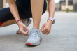 © Tarokmew - Young female tying running shoes before running.