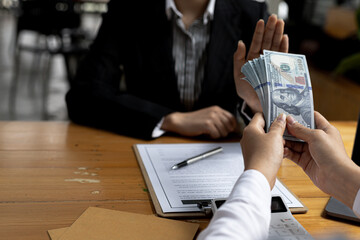 Wall Mural - Business man raised her hand to deny accepting a bribe from a business partner, a brown envelope containing a large number of dollar bills as money for bribery, a corruption concept.