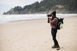 © Cavan Images - Young Woman taking photograph alone on Oregon beach