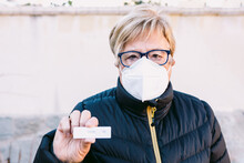 Elderly Lady On The Street, Wearing A White Mask, With A Negative Antigen Test. Concept Covid-19, Ihu, Delta, Omicron, Detection Test And Pandemic.