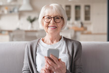 Closeup Cropped Front View Photo Of Senior Old Elderly Caucasian Woman Grandmother Using Smart Phone Cellphone For E-banking E-commerce, Surfing Social Media Online At Home