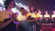 Multiracial young men in yellow team t shirts waving and clapping hands while taking part in modern gaming tournament