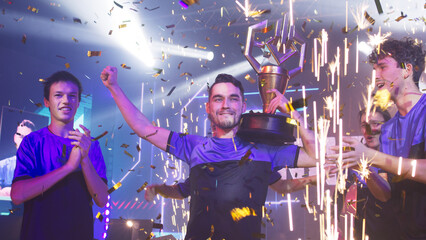 Wall Mural - Esport gamers team with golden trophy celebrating victory amidst confetti and pyrotechnics after professional esports competition