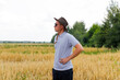 Crop and harvest. Portrait of farmer standing in gold wheat field with blue sky in background. Young man wearing sunglasses and cowboy hat in a field examining wheat crop. Oats industry