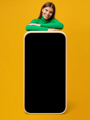 Wall Mural - Happy young woman standing behind blank screen of huge phone, mockup for app