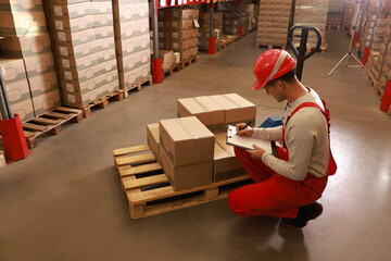 Wall Mural - Worker holding clipboard near pallet with boxes in warehouse