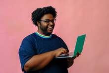 Young African American Man Working With Laptop In The Studio Over Pink Background