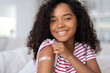 vaccinated African American woman showing arm with medical plaster patch Plaster On Shoulder, black female after getting vaccine dose against covid. Healthcare immunization, coronavirus vaccination