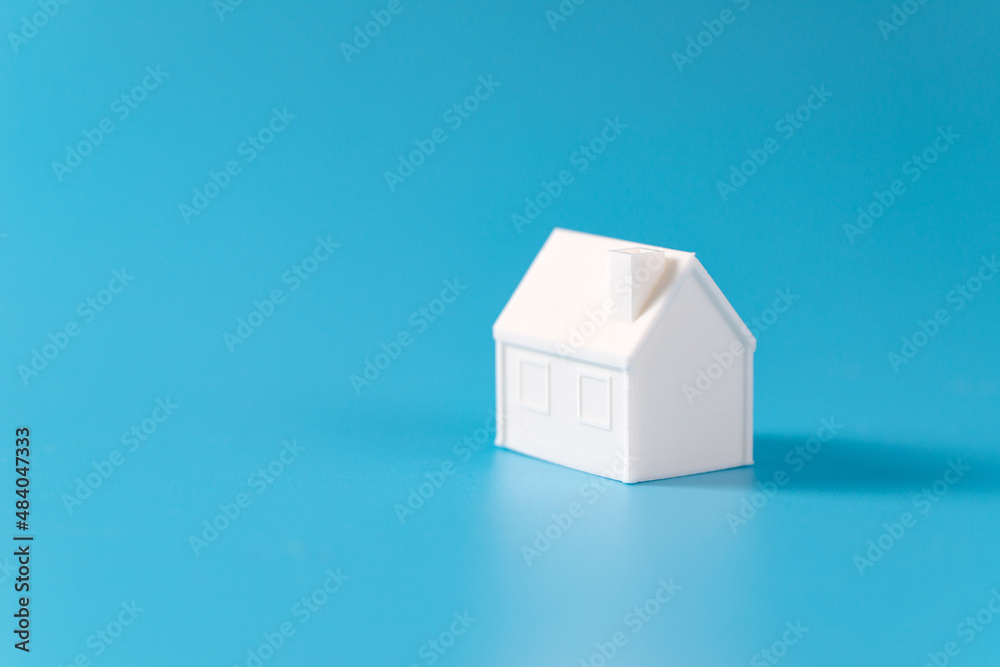 Single miniature 3D printed model house on blue background for home or ...